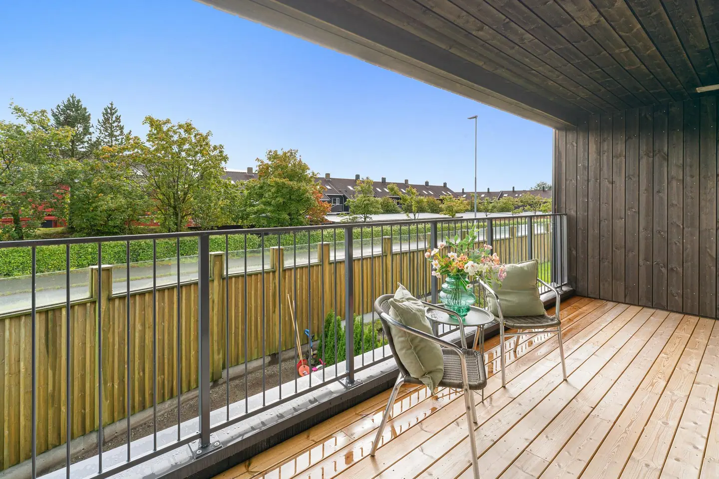 Fin og lun terrasse ut fra stue med utsikt over nærområdet. Overbygget tak, skjermet for vær og vind.