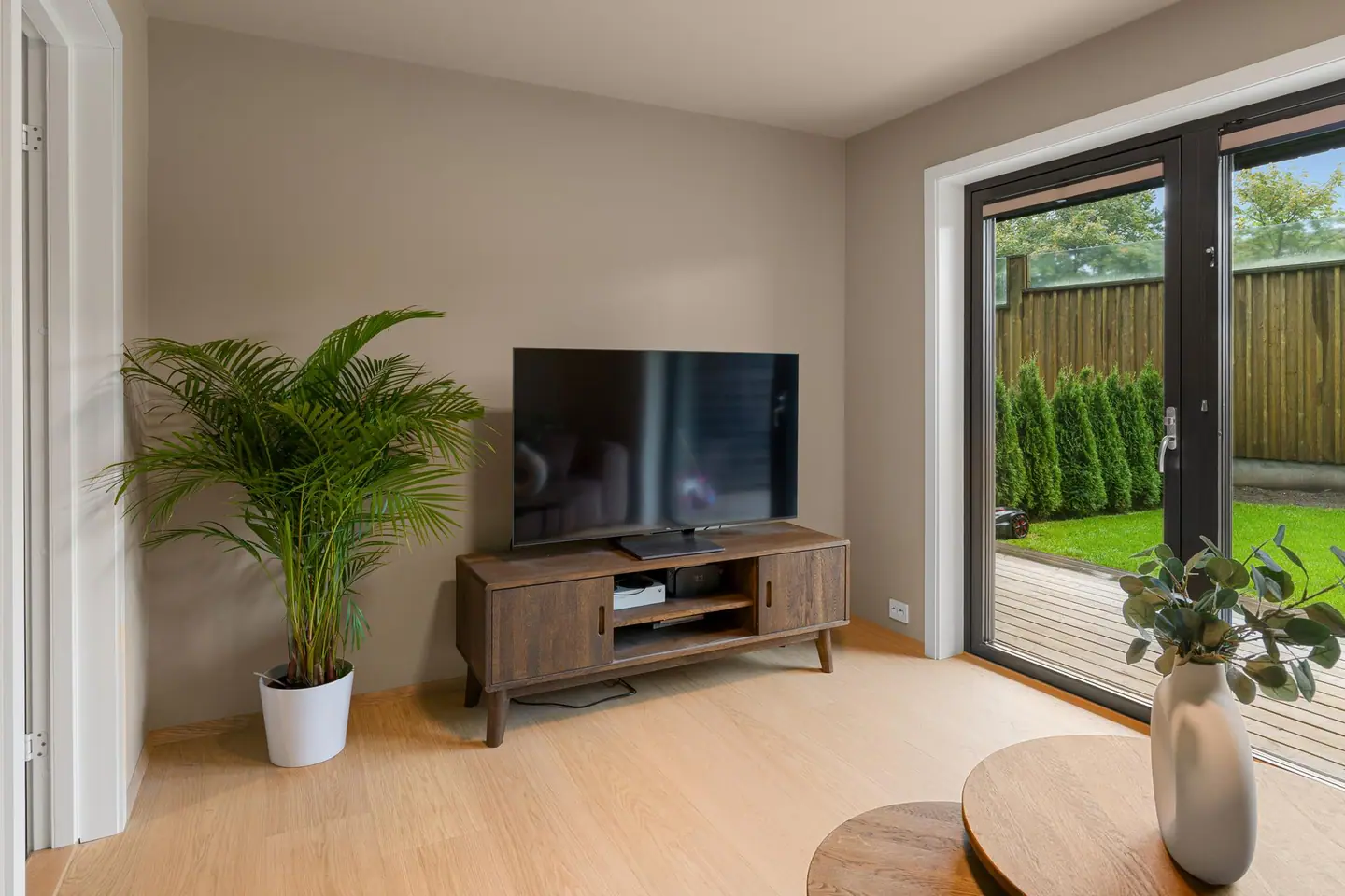 Tv-stue i første etasje med parkett på gulv og utgang til hage og veranda.