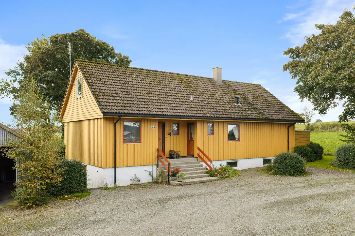 Inngangsparti med betongtrapp og adkomst fra det gruslagte gårdsrommet.