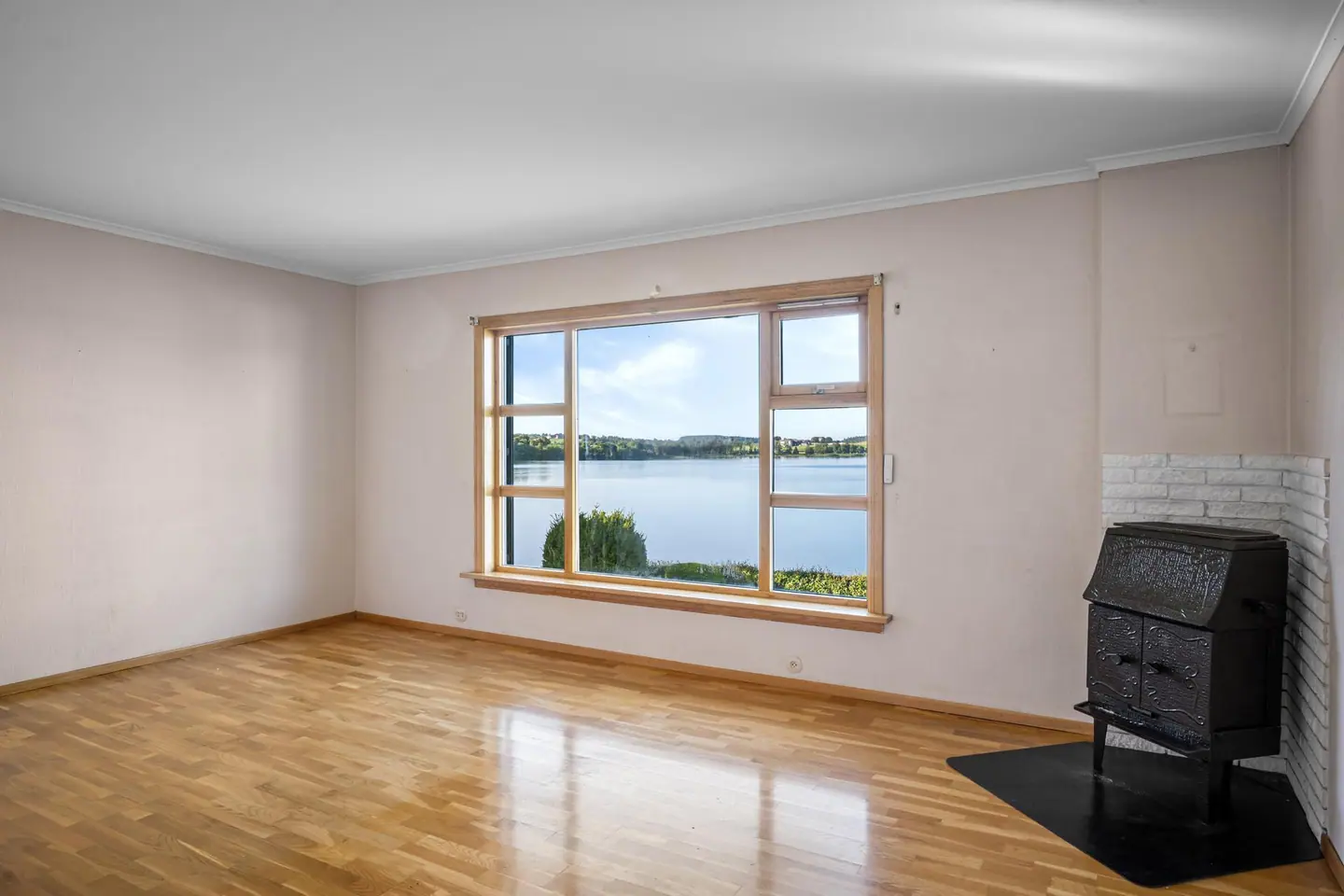Stuen har parkett på gulvet og en eldre vedovn tilknyttet mursteinspipe.