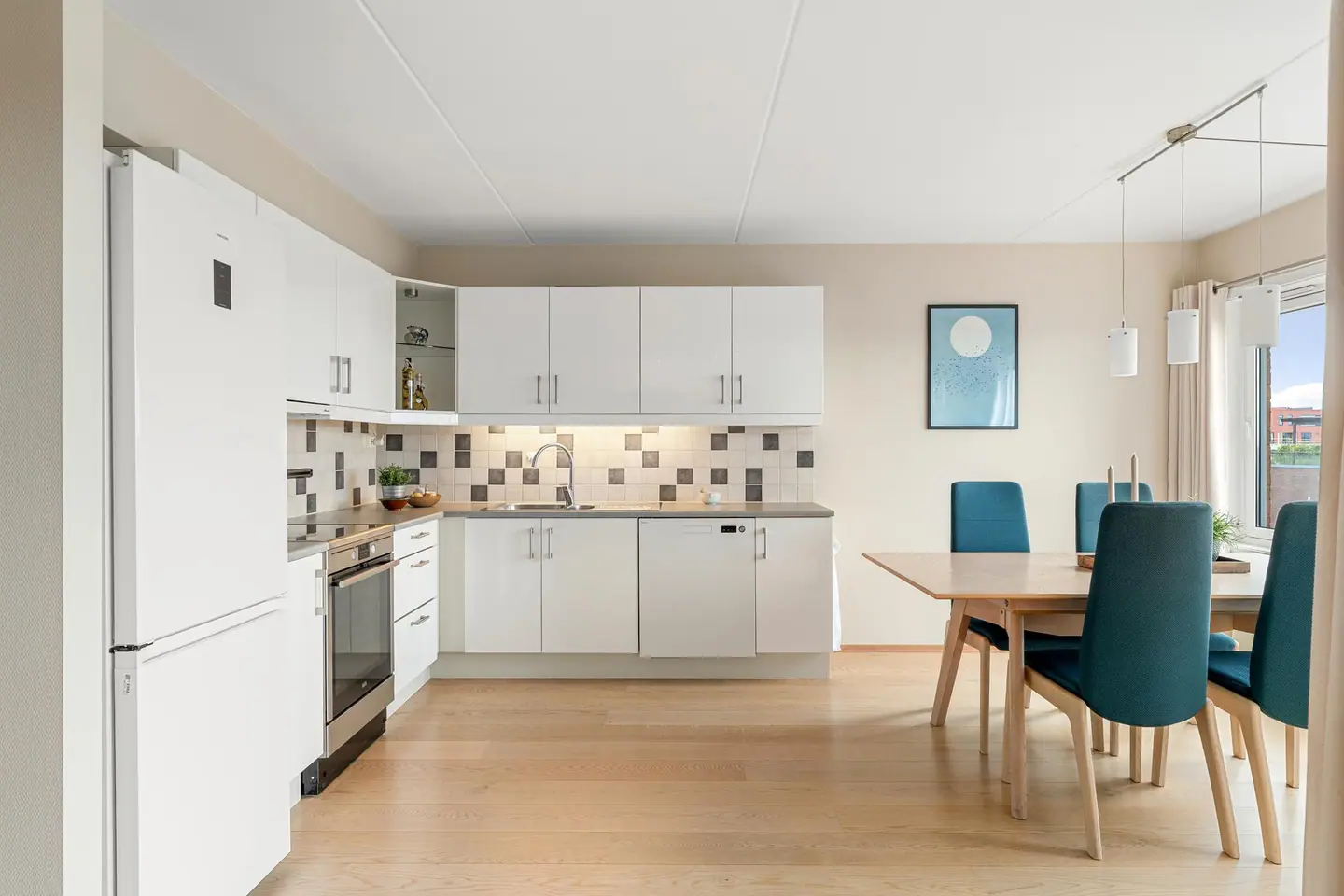 Kjøkkeninnredningen har glatte hvite fronter og benkeplate av laminat, med god benke- og oppbevaringsplass.