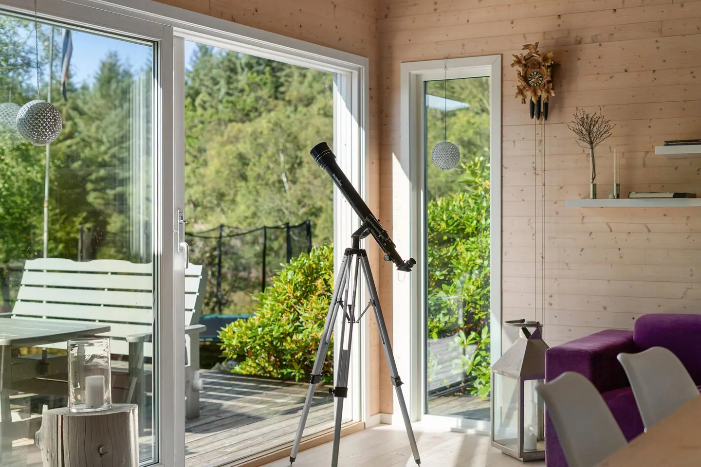 Store skyvedører i glass åpner opp mot terrassen og naturen utenfor.