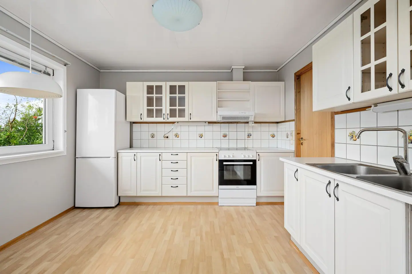 Kjøkkeninnredning med hvite profilerte fronter og laminat benkeplate.