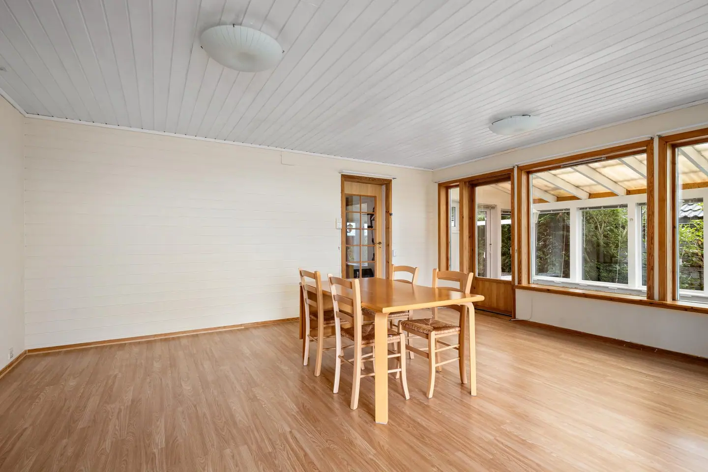 Store vindusflater og dørforbindelse inn mot drivhuset.